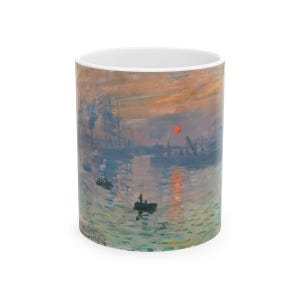 May include: A white ceramic mug with a colorful painting of a sunrise over a harbor. The painting features a red sun, blue water, and a hazy sky.