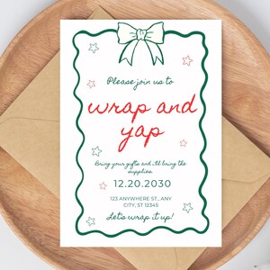 May include: A white invitation card with a green border and bow graphic, featuring the text "wrap and yap" in red. The card is on a wooden plate with a brown envelope, with cotton accents.