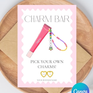 May include: A pink card with the words "Charm Bar" and "Pick Your Own Charms!" features a lip gloss illustration with a charm bracelet. The card is on a wooden tray with a brown envelope and cotton accents.