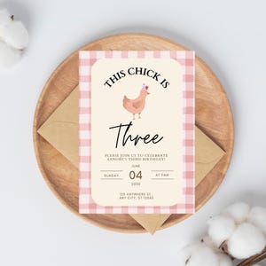 Puede incluir: Invitación de cumpleaños con estampado de cuadros rosa y blanco con un pollo de dibujos animados con una corona. El texto dice "This chick is three" e incluye detalles para una fiesta de cumpleaños.