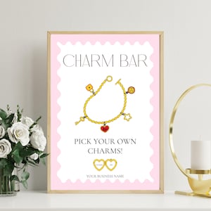 Könnte beinhalten: Ein gerahmter Druck mit einem rosa Rand und den Worten "CHARM BAR" in Schwarz. Darunter eine goldene Charm-Armband-Illustration mit verschiedenen Charms, darunter ein Schlüssel, ein Herz und ein Stern. Der Text "PICK YOUR OWN CHARMS!" steht darunter.