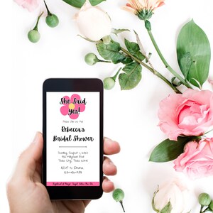 May include: A smartphone displaying a pink and yellow floral design with the text "She Said yes!" and "Rebecca's Bridal Shower". The text also includes the date, time, location, and RSVP information for the event.