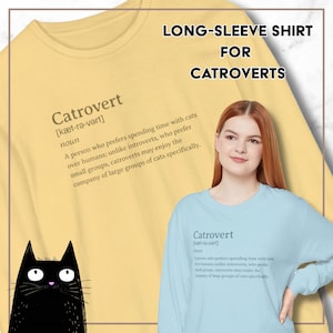 May include: A light yellow long-sleeve shirt with the word "Catrovert" and its definition printed on it. The shirt is for cat lovers. A black cat illustration is in the lower left corner.