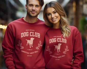 May include: Red crewneck sweatshirts with a white graphic design featuring a dog silhouette, the text "Bark Brigade Dog Club", and the words "Pawsitive Vibes Only" and "Est. 2022".