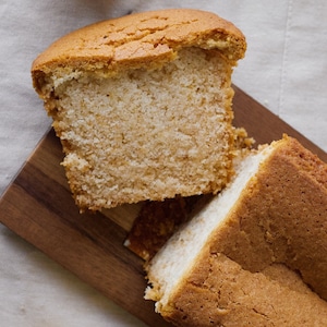 May include: Two slices of freshly baked bread on a wooden cutting board. The bread is light brown and has a soft, fluffy texture.