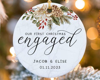 May include: White marble Christmas ornament with a floral design and the text "Our First Christmas Engaged Jacob & Elise 01.11.2023"