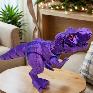 Könnte beinhalten: Ein lila Spielzeug-Dinosaurier mit roten Augen. Der Dinosaurier steht auf einer Holzoberfläche.