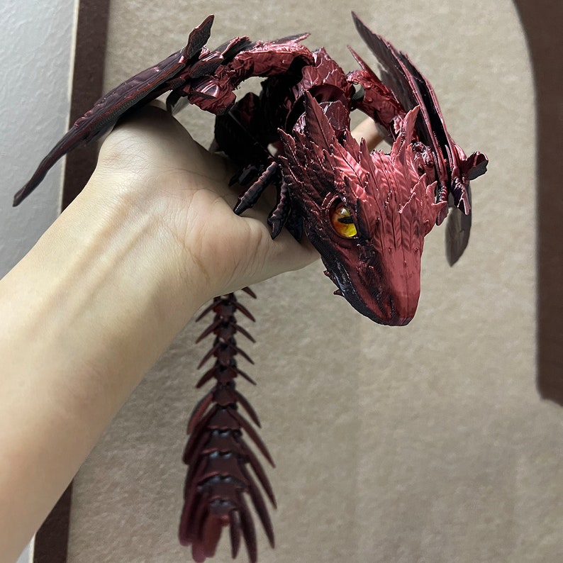 Puede incluir: Una figura de drag&oacute;n rojo con una textura escamosa detallada y una cola larga y segmentada. El drag&oacute;n tiene una expresi&oacute;n feroz y ojos amarillos brillantes.