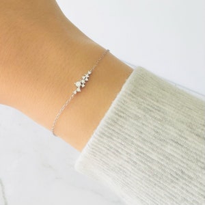 Pode incluir: Um delicado bracelete de corrente de prata com um grupo de pequenos diamantes brilhantes dispostos em fila.
