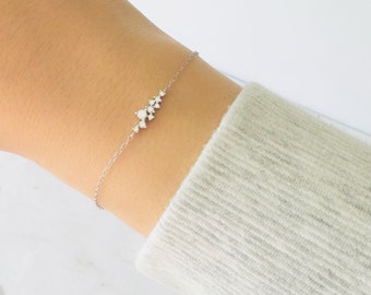 May include: A delicate silver chain bracelet with a cluster of small, sparkling diamonds set in a row.