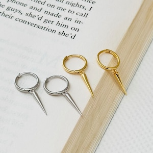 May include: Two pairs of hoop earrings with a pointed spike dangle. One pair is silver and the other is gold.