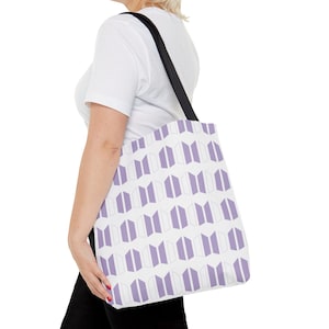 Könnte beinhalten: Eine weiße Einkaufstasche mit einem geometrischen Muster in Lila und Weiß. Das Muster besteht aus wiederholten Bildern des BTS-Logos.