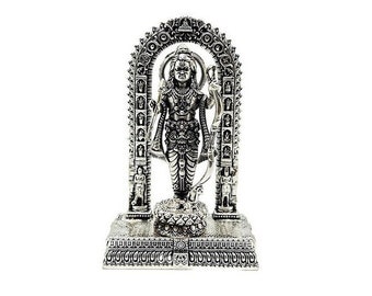 May include: Silver statue of a Hindu deity standing in a decorative archway. The deity is holding a weapon in one hand and a bow in the other. The statue is on a base with intricate details.