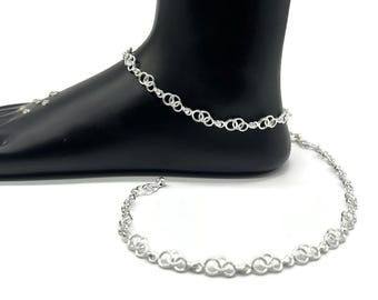 May include: A silver anklet with a delicate chain design. The anklet is made of small, interconnected circles.