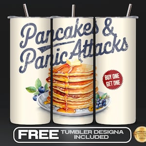 May include: A white tumbler with a design of pancakes and the text "Pancakes & Panic Attacks" in a vintage style. The design also includes a stack of pancakes with syrup and blueberries. The text "Buy One Get One" is also included in a red circle.
