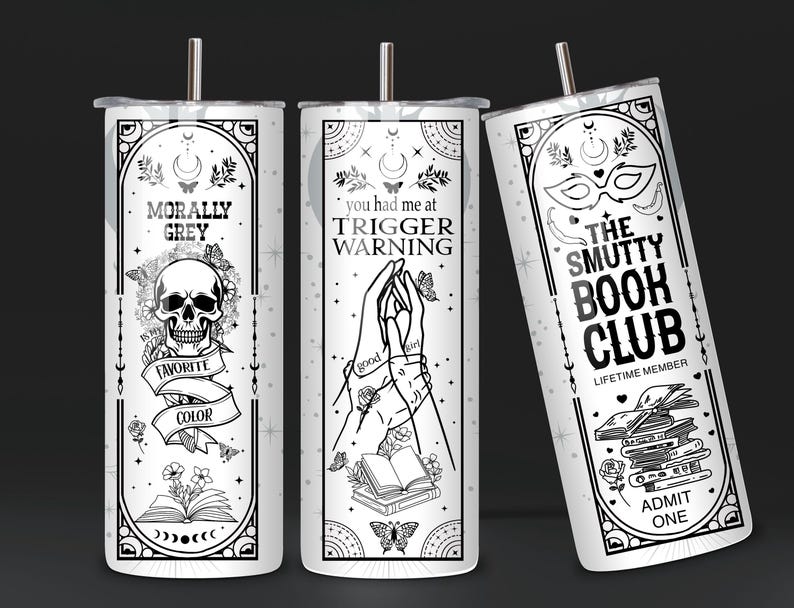 May include: Three white tumblers with black designs. The first tumbler has a skull and crossbones with the text "Morally Grey" and "Favorite Color". The second tumbler has two hands holding a book with the text "You had me at Trigger Warning". The third tumbler has a mask and the text "The Smutty Book Club, Lifetime Member, Admit One".