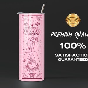 May include: Pink stainless steel tumbler with a design of two hands holding a book and the text "you had me at trigger warning" with butterflies and flowers.