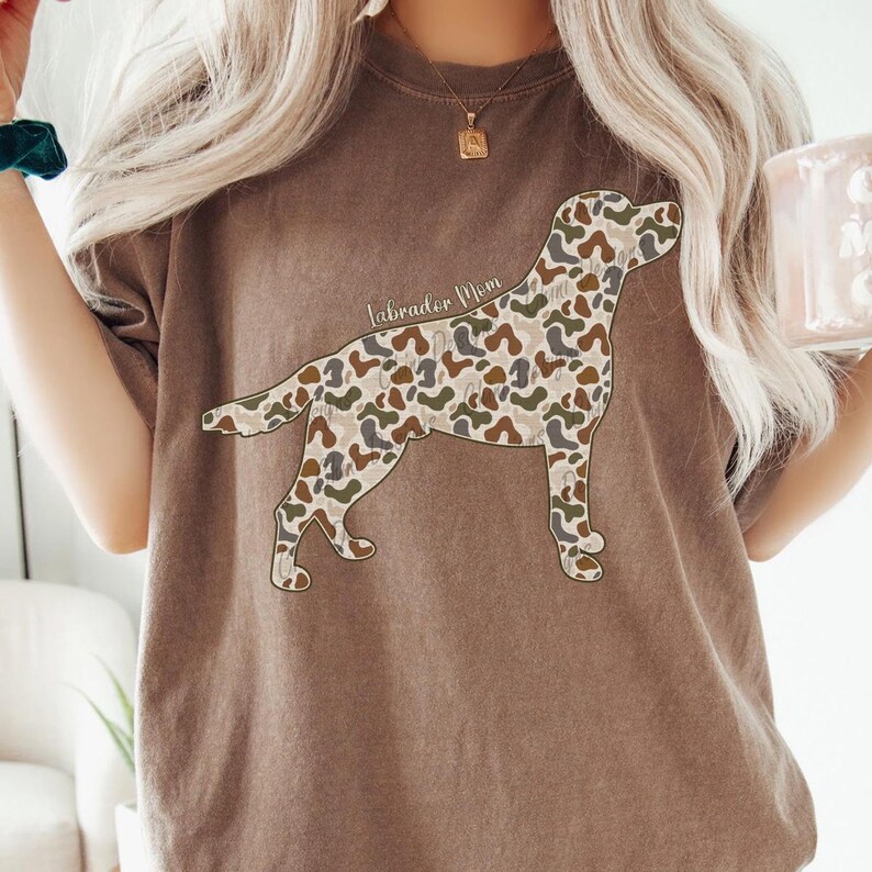 A woman wearing a brown t-shirt with a camouflage dog design printed on it.