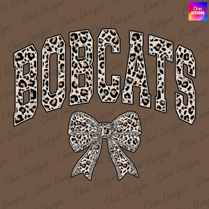 Puede incluir: Un diseño gráfico marrón con la palabra "BOBCATS" en letras grandes y en bloque con un estampado de leopardo. Debajo, un lazo a juego con estampado de leopardo. El fondo es de color marrón liso.