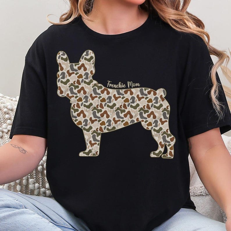 A woman wearing a black t-shirt with a camouflage pattern of a dog, specifically a French Bulldog, printed on it.