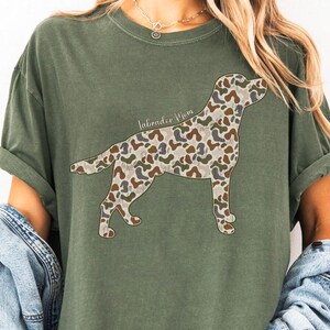A woman wearing a green t-shirt with a camouflage dog design on it.