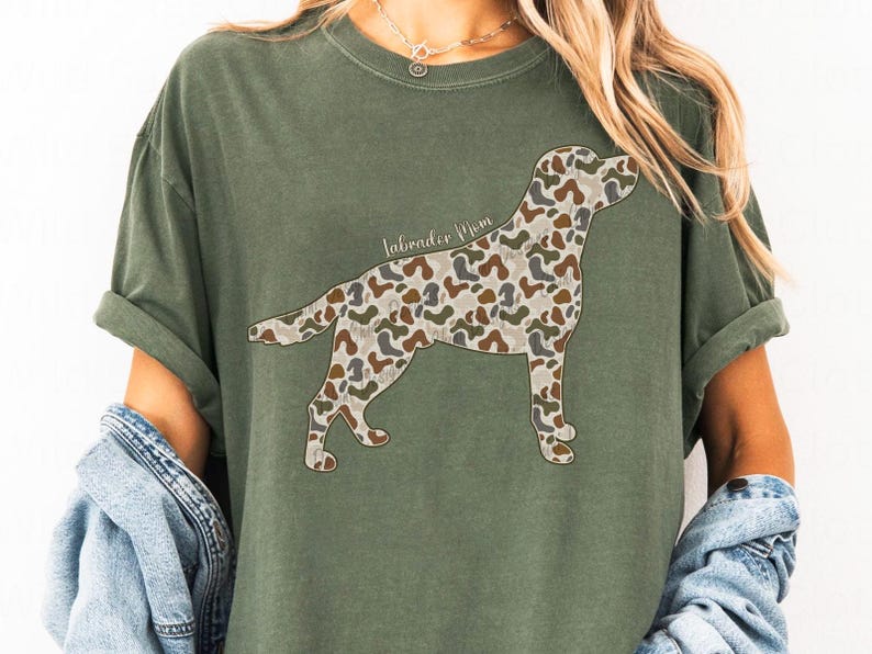 A woman wearing a green t-shirt with a camouflage dog design on it.