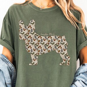A woman wearing a green t-shirt with a camouflage print of a dog.