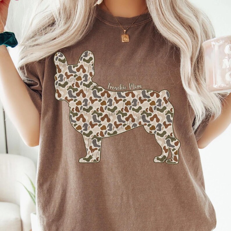 A woman wearing a brown t-shirt with a camouflage dog design printed on it.