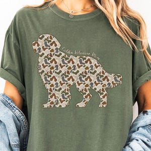 A woman wearing a green t-shirt with a camouflage dog silhouette and the text "Golden retriever mom" printed on it.
