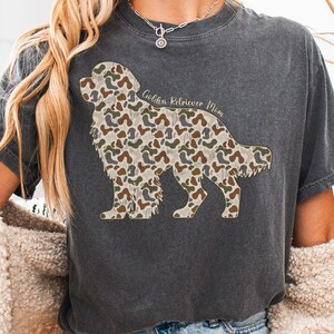 A person wearing a gray t-shirt with a camouflage print of a dog, and a necklace around their neck.