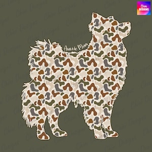 May include: Aussie Mom design featuring a silhouette of a dog with a camouflage pattern in shades of brown, green, and beige. The text "Aussie Mom" is in a script font. The background is a solid olive green.