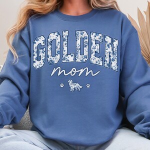 a woman wearing a sweatshirt that says golden mom