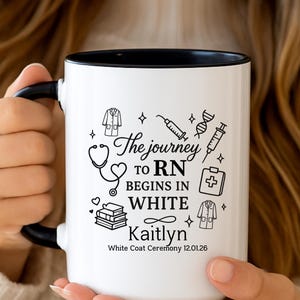 Puede incluir: Taza de cerámica blanca con interior y asa negros. La taza presenta el texto "The journey to RN begins in WHITE" junto con ilustraciones médicas y el nombre "Kaitlyn". La fecha "12.01.26" también está impresa en la taza.