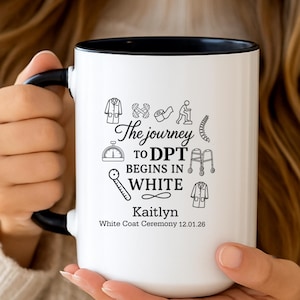 May include: White ceramic mug with a black interior and handle. The mug features the text "The journey to DPT begins in white" with medical-related icons and the name "Kaitlyn". White Coat Ceremony 12.01.26 is also printed on the mug.