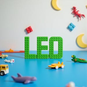 May include: A vibrant image features the name "LEO" spelled out in bright green building blocks. The name is surrounded by colorful toy vehicles, animals, and decorative shapes, including a yellow crescent moon and red and blue blocks, all set against a blue surface.