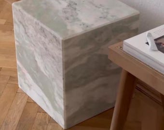 May include: A square, white marble end table with green and gray veining. The table is sitting on a wooden floor.