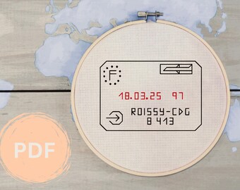 May include: A white embroidery hoop with a black and white design of a flight boarding pass. The boarding pass has the text "F", "18.03.25 97", "ROISSY-CDG", and "8413".