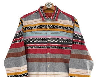 May include: A long-sleeved button-down shirt with a colorful striped pattern. The shirt has a geometric design with red, blue, yellow, and white stripes.