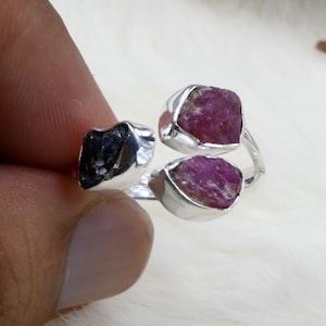 Könnte beinhalten: Ein Silberring mit drei rohen Edelsteinen. Zwei der Steine sind rosa und einer ist schwarz.