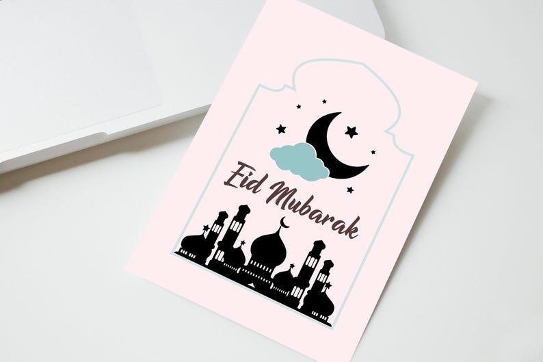 May include: A pink card with a white border and the text "Eid Mubarak" in brown lettering. The card features a black silhouette of a mosque with a crescent moon and stars in the sky.