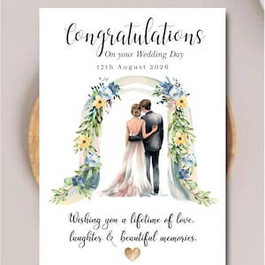 May include: A wedding greeting card featuring the text Congratulations On your Wedding Day 17th August 2026. The design shows a couple standing under a watercolor floral arch with blue and yellow flowers, and the text Wishing you a lifetime of love, laughter & beautiful memories with a gold heart.