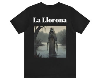 Könnte beinhalten: Schwarzes T-Shirt mit einem Grafikdruck einer Frau in einem weißen Kleid, die in einem Gewässer steht. Der Text "La Llorona" ist in Weiß über dem Grafikdruck gedruckt.