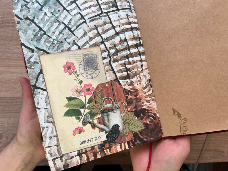 May include: A brown and white journal with a floral design and a watering can with a bird on it. The journal has a red string closure and the text "BRIGHT DAY" on the front.