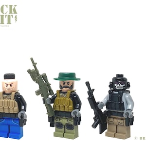 May include: Three Lego minifigures dressed as soldiers. The figure on the left is wearing a black shirt, blue jeans, and a tan vest. The figure in the middle is wearing a green hat, a tan vest, and a black shirt. The figure on the right is wearing a black helmet, a gray shirt, and a tan vest. All three figures are holding weapons.