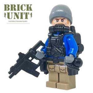 May include: A custom action minifigure from Brick Unit. The figure wears a blue jacket, black tactical vest, and a gray helmet. It holds a black rifle and has a gas mask. The figure has tan legs and a neutral expression.