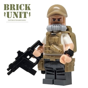 May include: A custom action minifigure wearing a tan cap, a white shirt, a tan tactical vest, and dark gray pants. The figure has a gray respirator mask, a tan backpack, and a black submachine gun. Text reads BRICK UNIT CUSTOM ACTION MINIFIGURES.