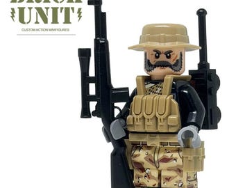 May include: A minifigure wearing a tan boonie hat, a black shirt, and desert camouflage pants. The figure has a tan tactical vest, a black backpack with an antenna, and holds a black sniper rifle. Text reads BRICK UNIT CUSTOM ACTION MINIFIGURES.