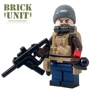 May include: A custom action minifigure from Brick Unit, wearing a gray beanie, a tactical vest, and blue pants. The minifigure has a black gas mask and is holding a black rifle. The text "BRICK UNIT" is visible.