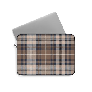 May include: A laptop sleeve with a plaid pattern in shades of brown, beige, and navy blue. The sleeve is open, revealing a silver laptop inside. The plaid design features a classic grid pattern, offering a stylish and protective accessory for laptops.