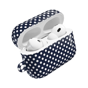 May include: A navy blue and white polka dot protective case for wireless earbuds. The case is open, revealing two white earbuds inside. The case has a small loop for attaching to a keychain or bag.